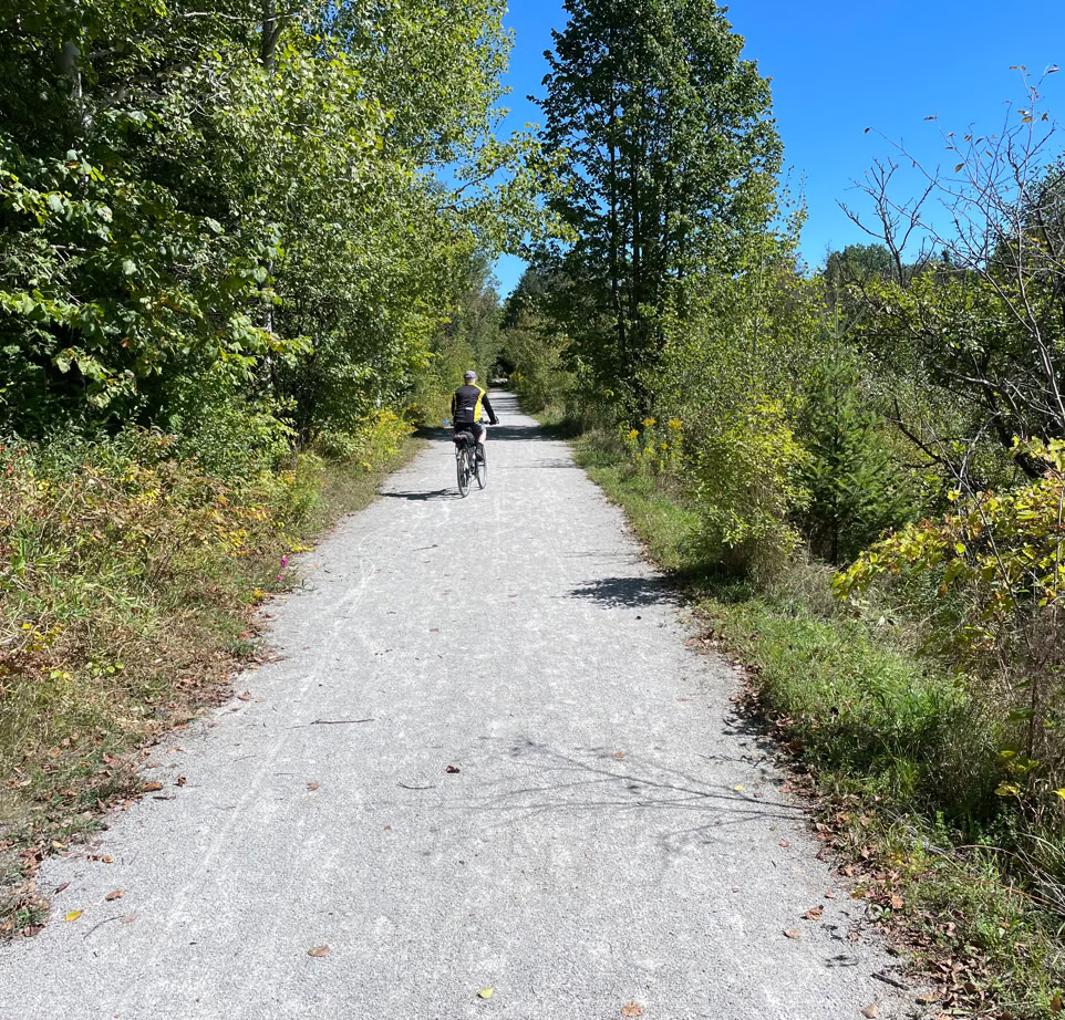 Early fall view of male cyclist on the Elora Cataract Trailway approaching HIllsburgh from the north