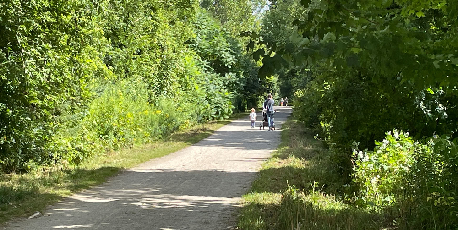 Picture of woman pushing a stroller, accompanied by a young child on the Elora Cataract Trailway in Fergus ON.